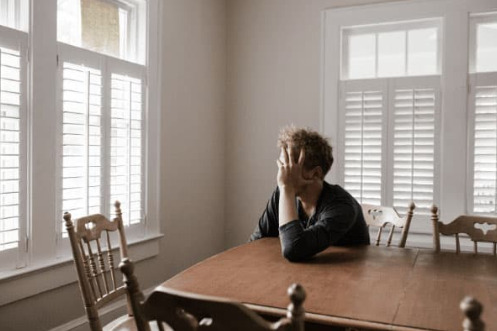 An anxious man stares out of a window