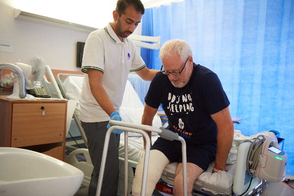 Knee replacement surgery patient being helped out of a hospital bed