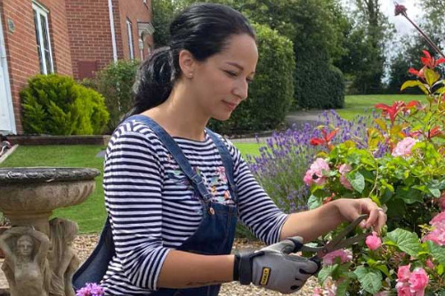 woman prunes some flowers in a garden