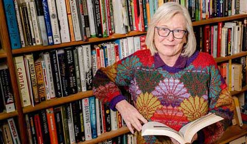 Valerie Stewart next to a wall of books